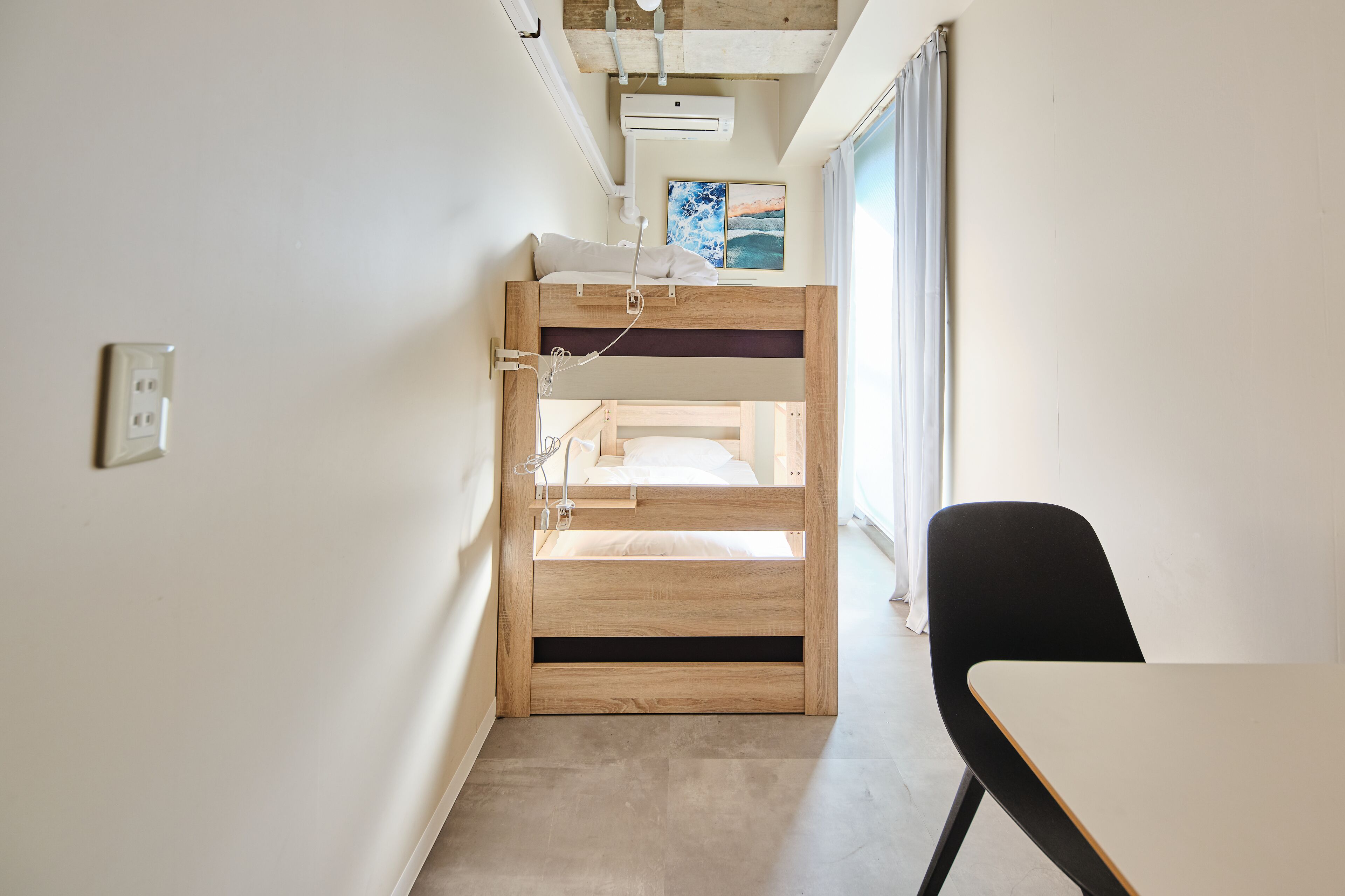 A compact room with a bunk bed, a small table, and a chair.