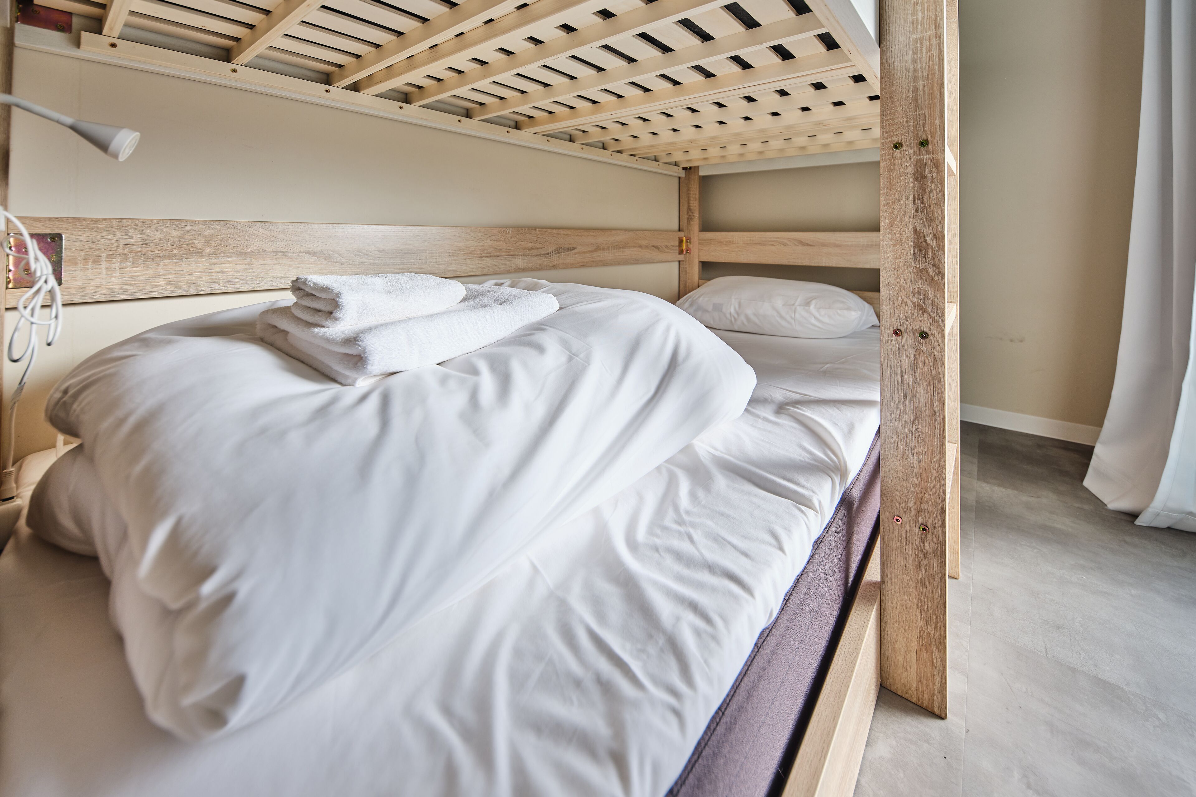 A bunk bed with white bedding and a wooden headboard.