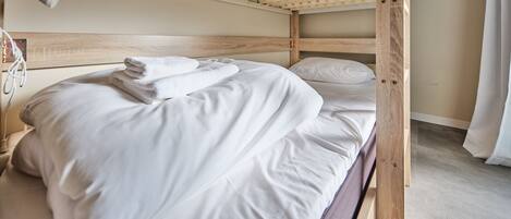 A bunk bed with white bedding and a wooden headboard.