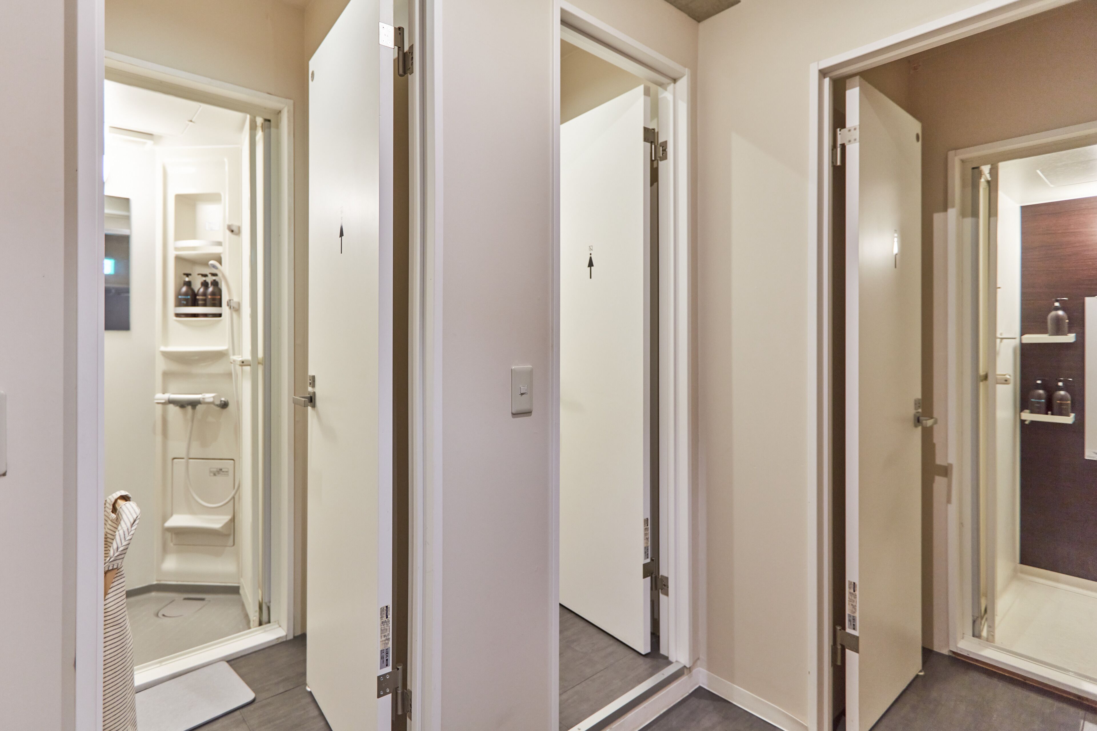 Un couloir avec un espace douche, une porte dotée d’une étagère et une porte avec un miroir.