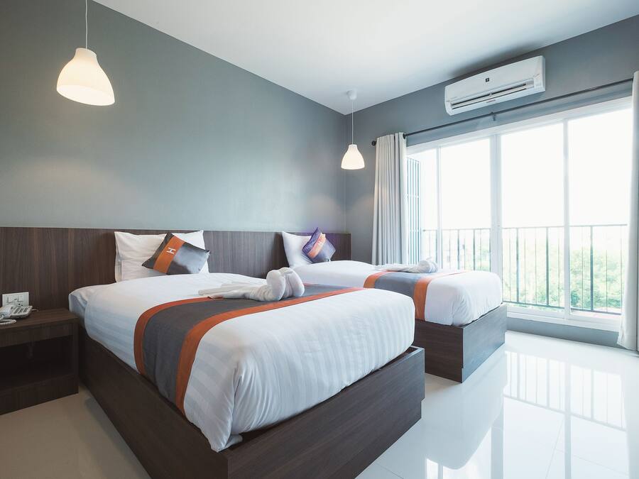 A modern hotel room with two beds, a nightstand with a phone, and a large window with curtains.