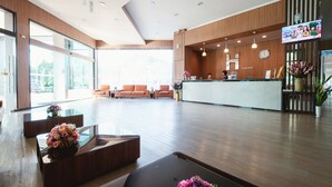 A modern hotel lobby with a reception desk, seating area, and large windows. - Hansanan Hotel (Phitsanulok)