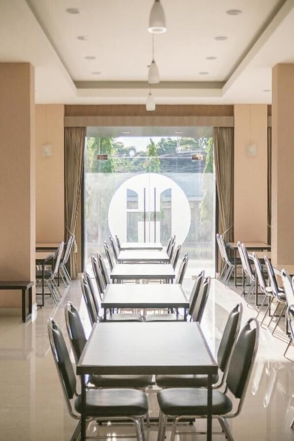 A conference room with a long table and chairs, large windows with a view of greenery, and a ceiling with recessed lighting. - Hansanan Hotel (Phitsanulok)
