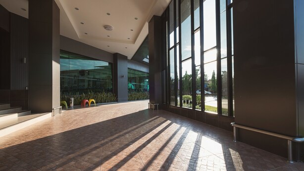 A spacious indoor area with large windows, a tiled floor, and a modern architectural design. - Hansanan Hotel (Phitsanulok)