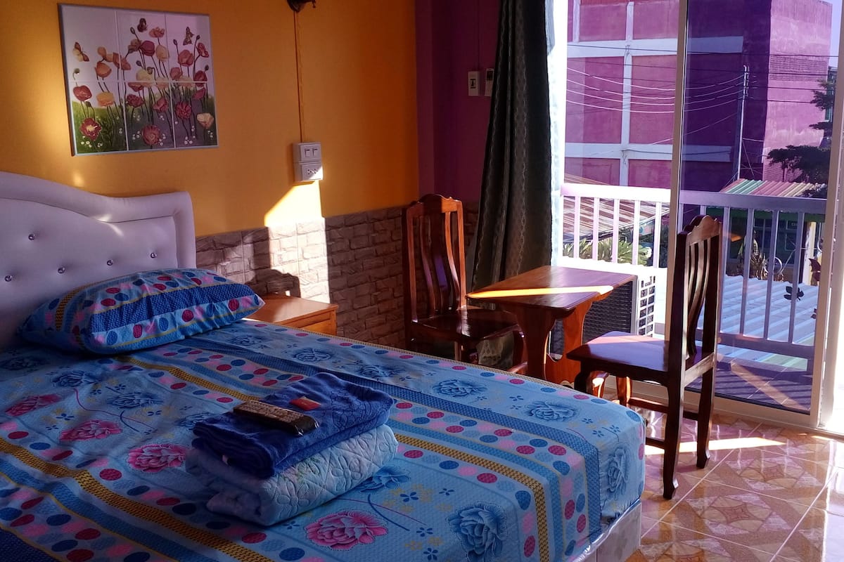 A bedroom with a bed, a nightstand, a chair, and a table.