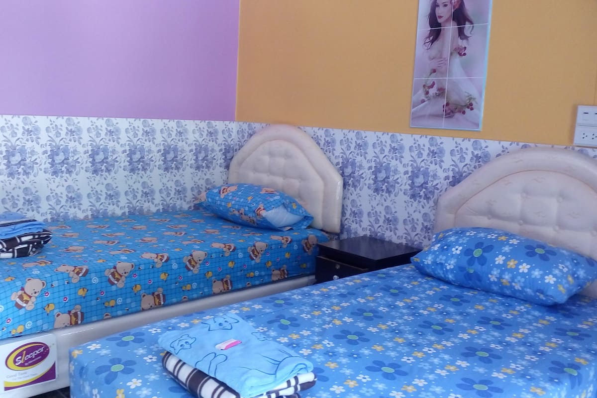 A bedroom with two beds, each with a floral bedspread and a teddy bear design.