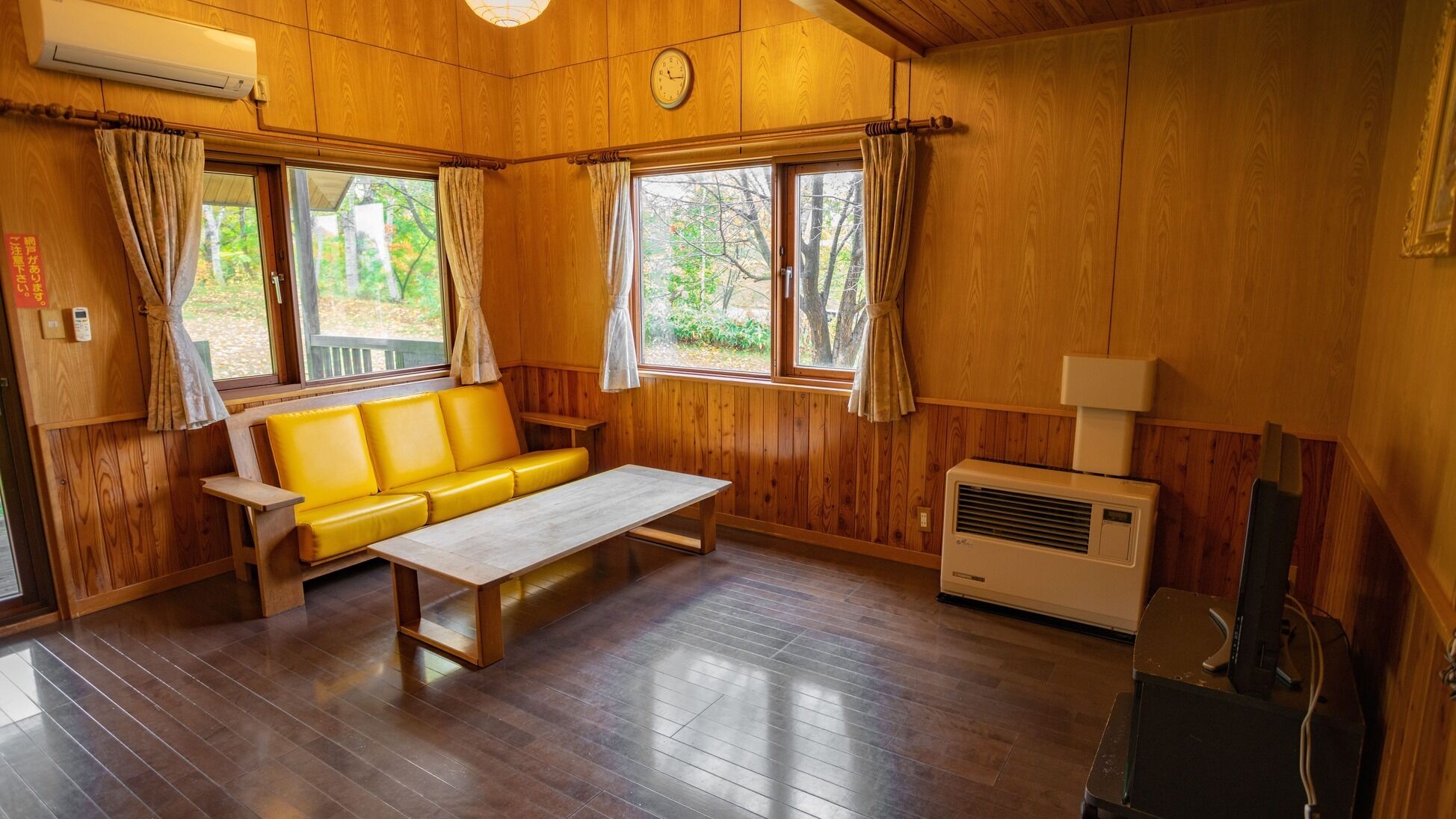 Una cabaña con interior de madera, un sofá, una mesa y un ventanal.