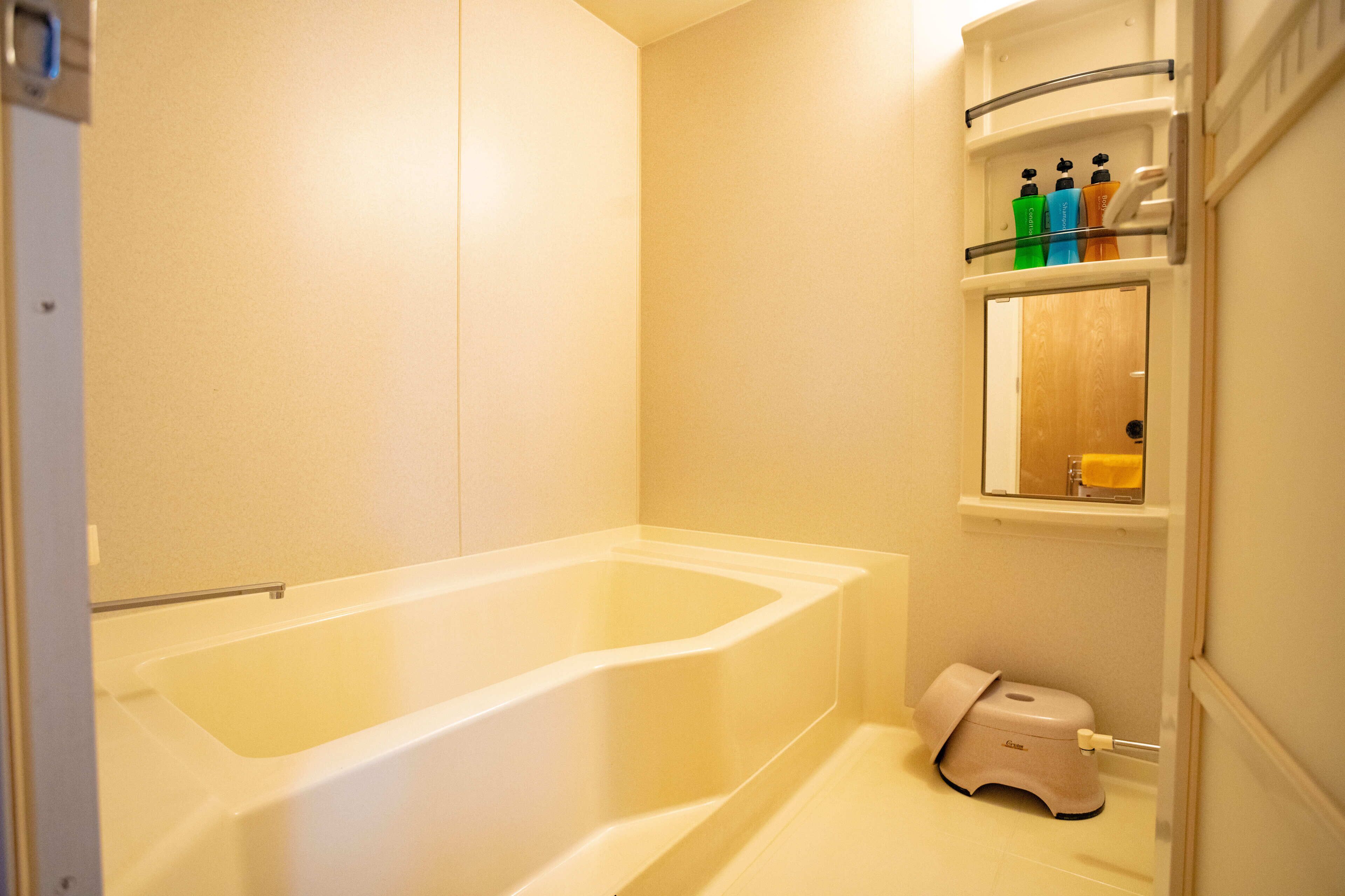 Une salle de bain équipée d’une baignoire, de toilettes et d’une étagère où sont rangés les articles de toilette.