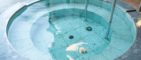 Una piscina circular con desagüe central, bordeada por un bordeado de azulejos.