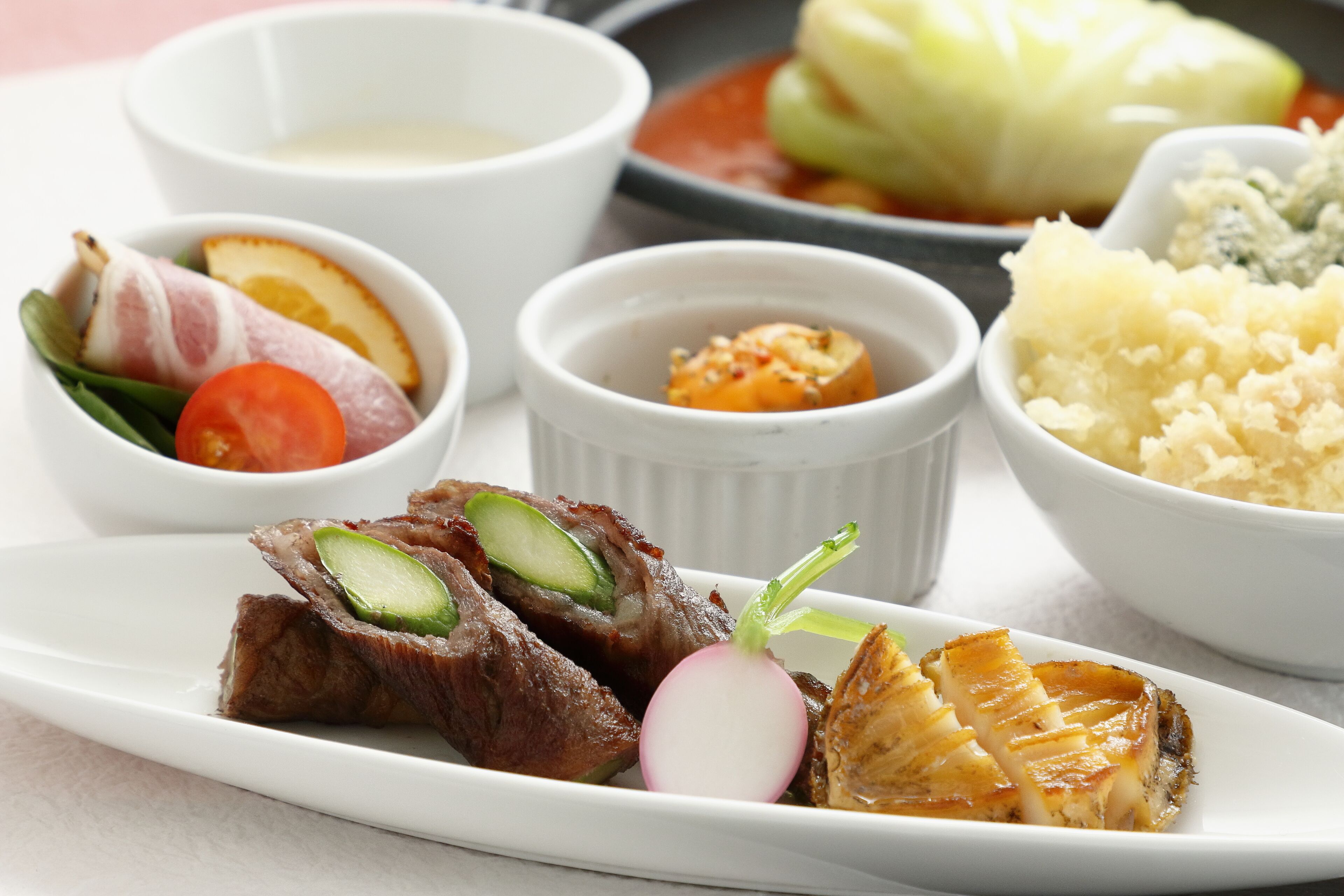 Une assiette blanche contenant divers aliments, notamment de la viande, des légumes et des sauces.