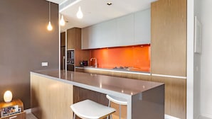 Une cuisine moderne dotée d’un îlot central, de tabourets de bar et de luminaires suspendus.