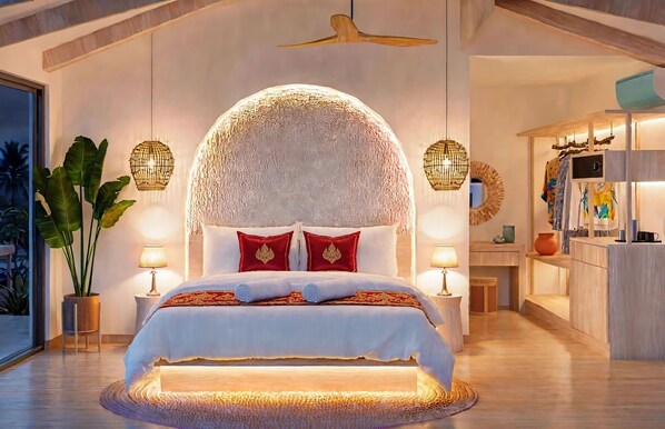 Ein Schlafzimmer mit einem großen Bett, zwei Nachttischen, einem Deckenventilator und Blick auf die Küche.