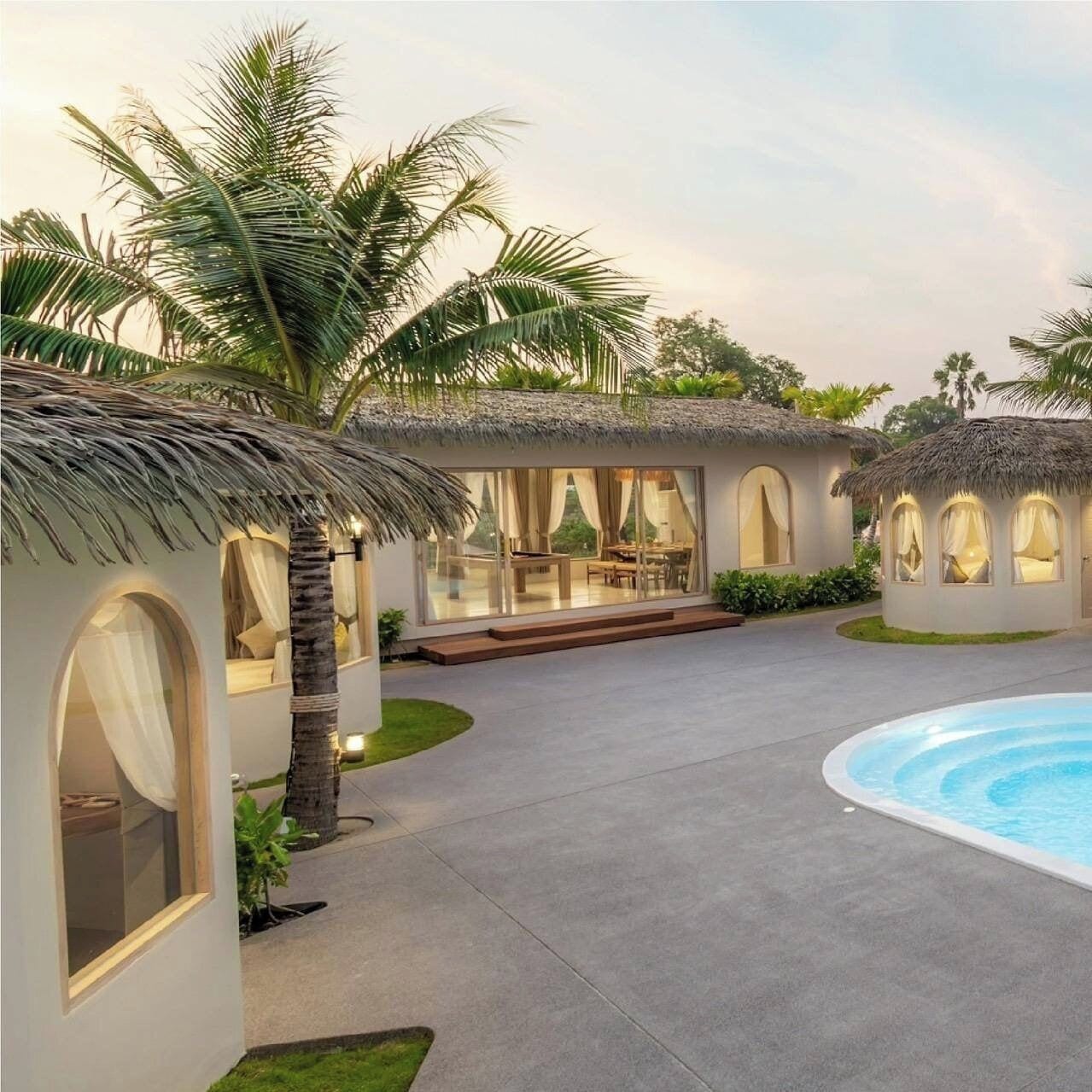 Un complexe hôtelier doté de bungalows aux toits de chaume, d’une piscine et d’un jardin bien entretenu.