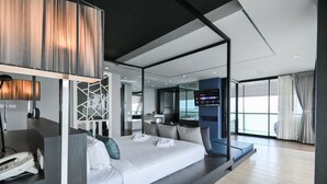 A modern hotel room with a large bed, a desk with a phone, and a TV.