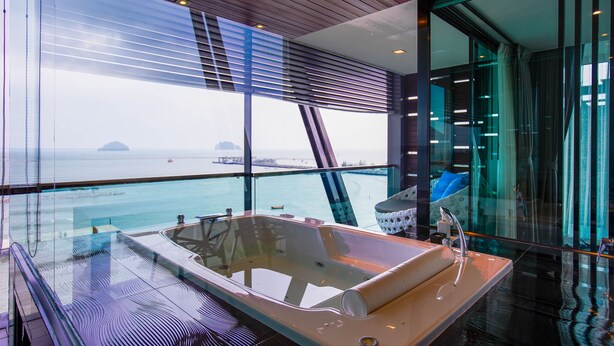 A modern interior with a large glass window, a hot tub, and a view of the sea.