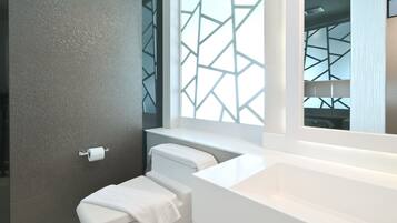 A modern bathroom with a large mirror, white fixtures, and a geometric patterned window.