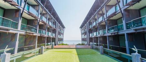 A modern hotel with a central courtyard, balconies, and a view of the sea.