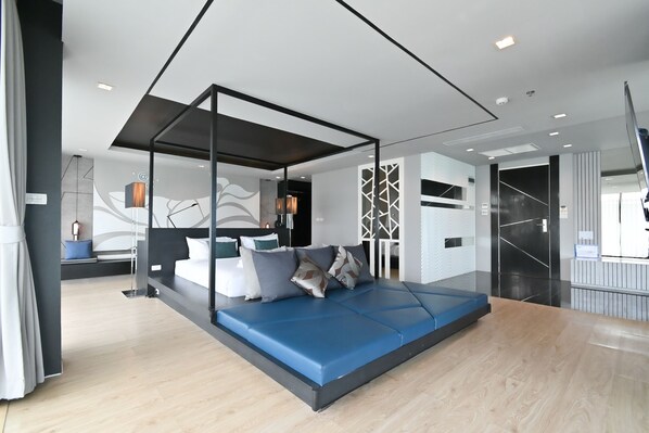 A modern bedroom with a hanging bed, a desk, and a view of the city. - @T Boutique Hotel (Prachuap Khiri Khan)