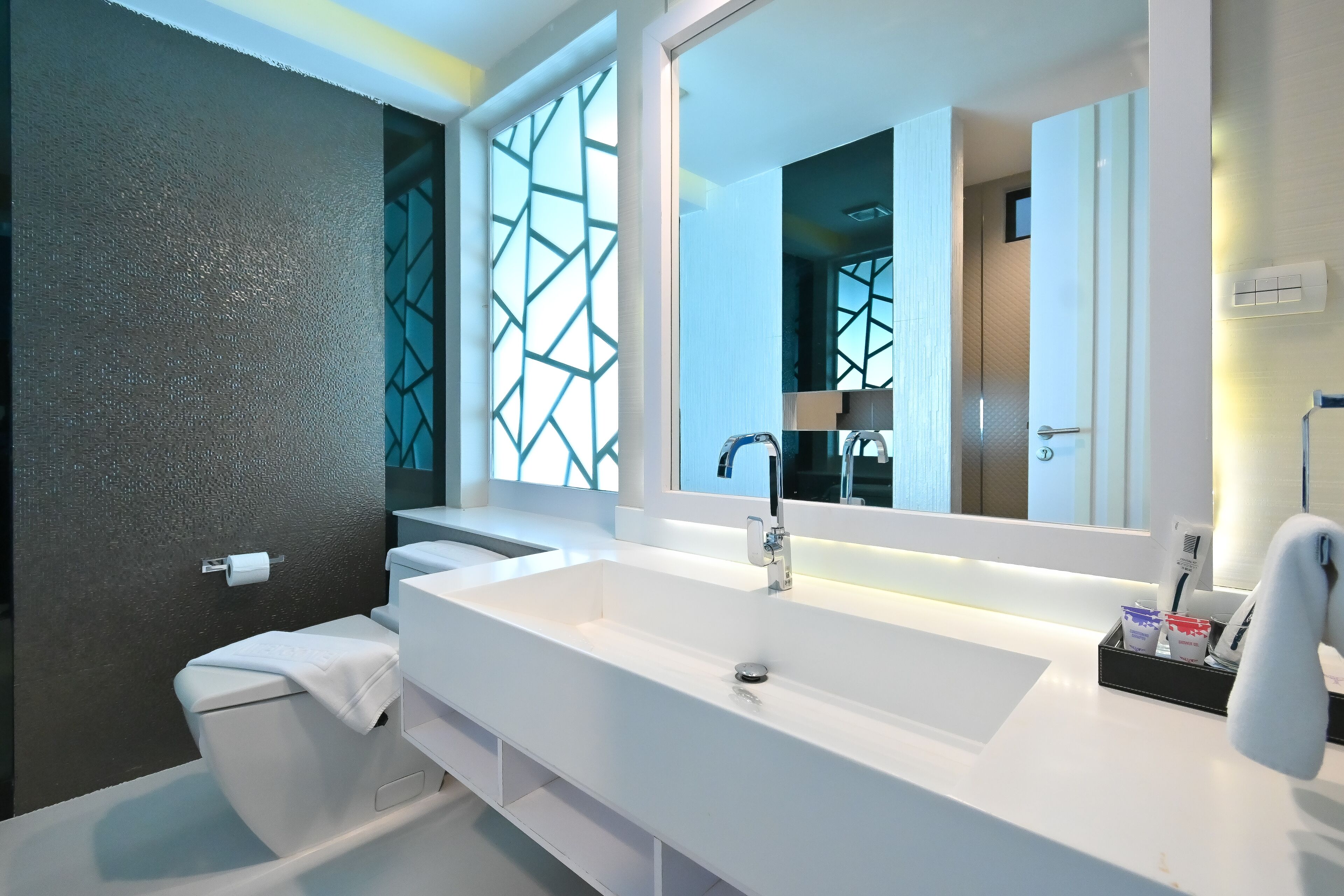 A modern bathroom with a white sink, large mirror, and a towel rack.