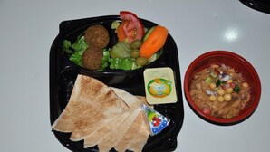 A meal with falafel, salad, pita bread, hummus, and a small container of cheese. - Sea Shell Hotel (Manama)