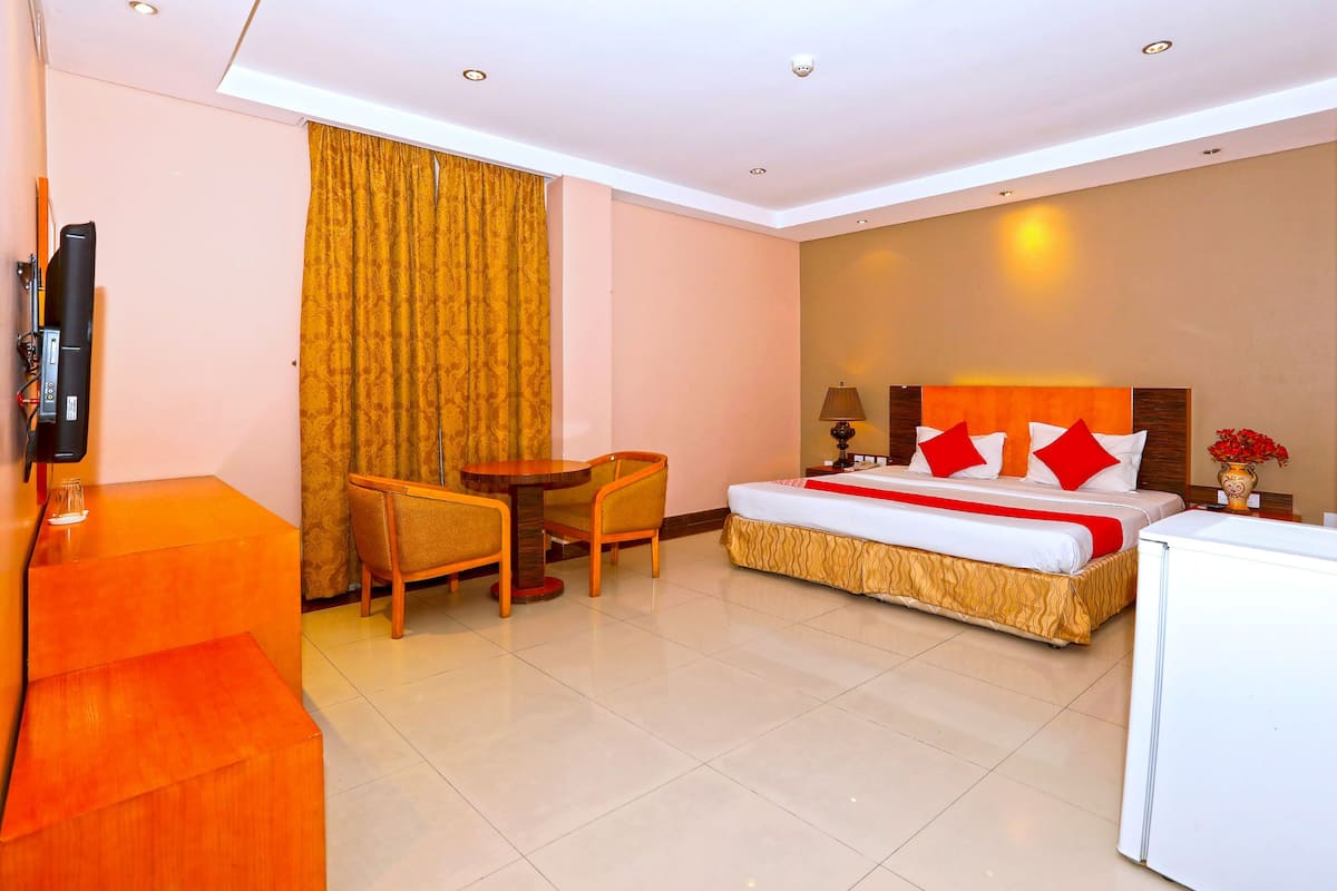 A hotel room with a bed, a desk, a chair, a television, and a window with curtains.