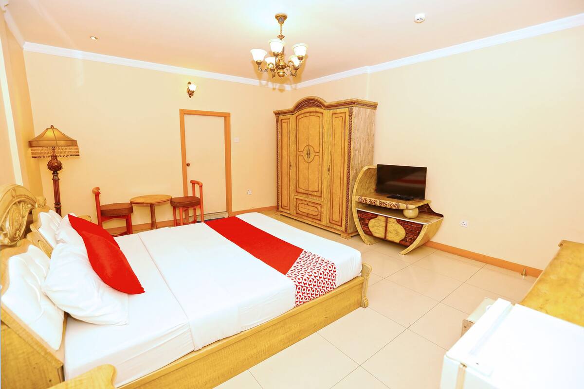 A hotel room with a bed, a wardrobe, a television, and a desk.