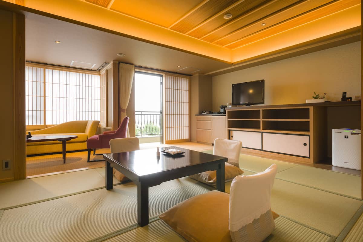 Ein traditioneller japanischer Raum mit Tatami-Böden, einem niedrigen Tisch und einer Couch.