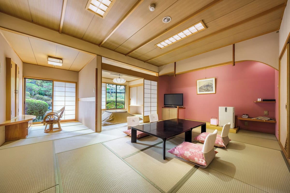 Ein traditioneller japanischer Raum mit Tatami-Bodenbelag, einem niedrigen Tisch und einem Fernseher.