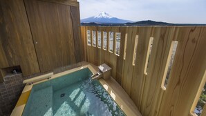 A hot tub with a wooden fence and a view of a snow-capped mountain. - Fujisan Onsen Hotel Kaneyamaen (Fujiyoshida)