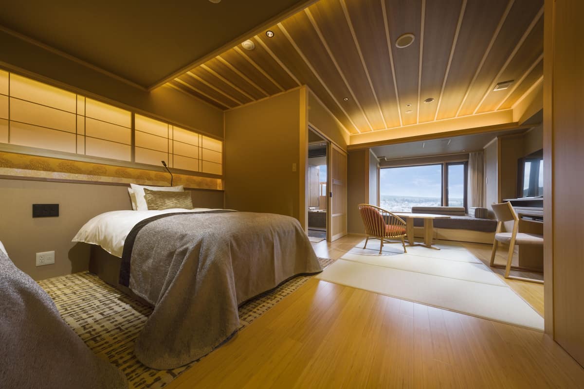 Ein modernes Schlafzimmer mit zwei Betten, einem Schreibtisch und Blick auf die Stadt.