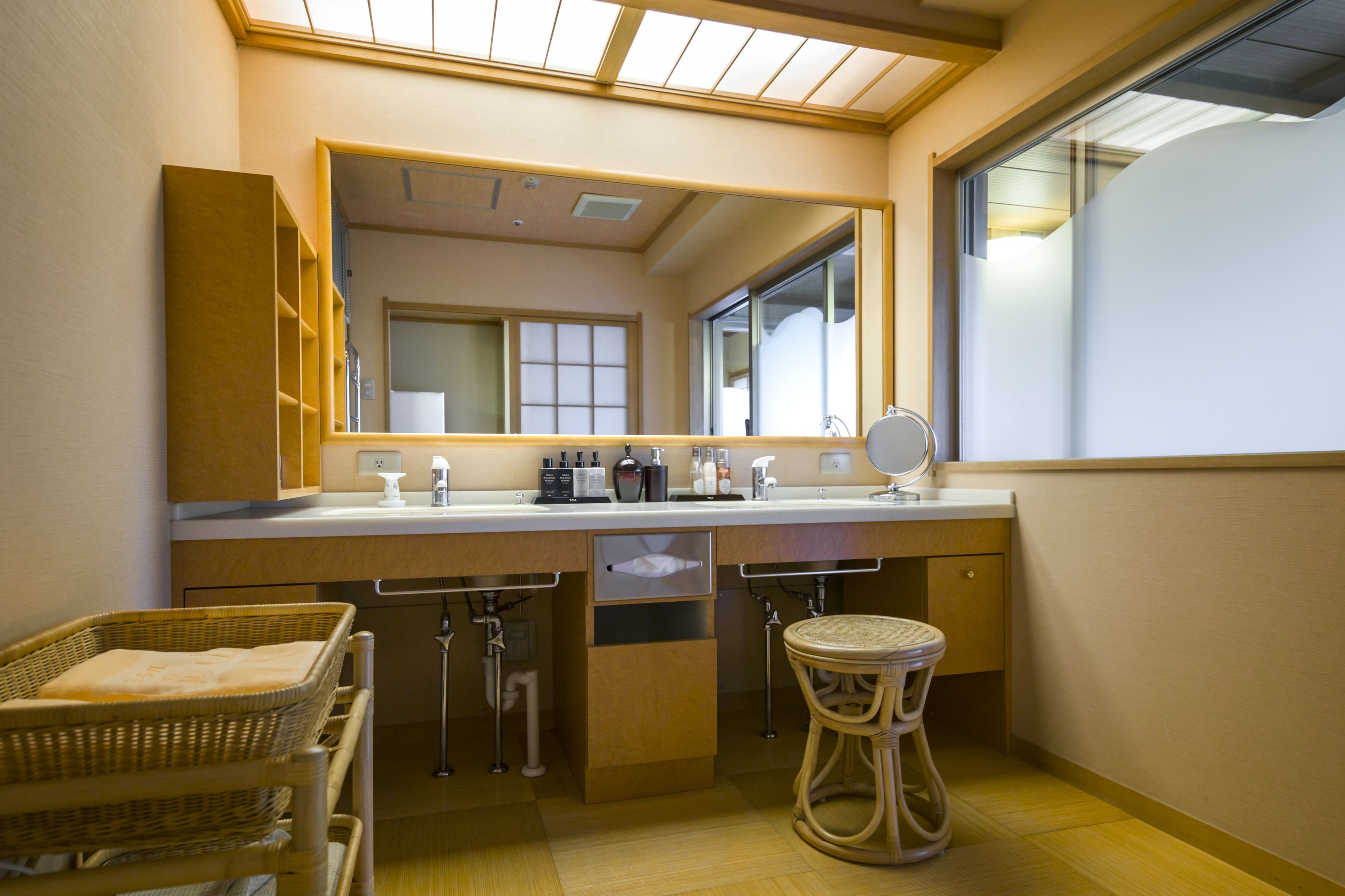 A bathroom with a large mirror, a sink, and a window.