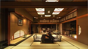 Una habitación japonesa tradicional con suelo de tatami, una mesa baja con cojines y puertas correderas.
