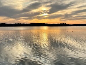 En stilla sjö vid solnedgången, med en skogbeklädd strand.