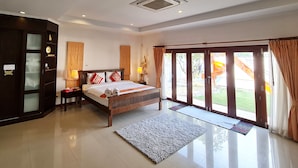 A spacious bedroom with a large bed, a wardrobe, and a sliding glass door leading to a balcony. - Thiva Pool Villa Hua Hin (Hua Hin)
