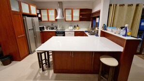 A modern kitchen with wooden cabinets, a central island, and stainless steel appliances. - Thiva Pool Villa Hua Hin (Hua Hin)