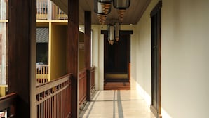A corridor with wooden railings and a tiled floor, leading to a dark doorway.