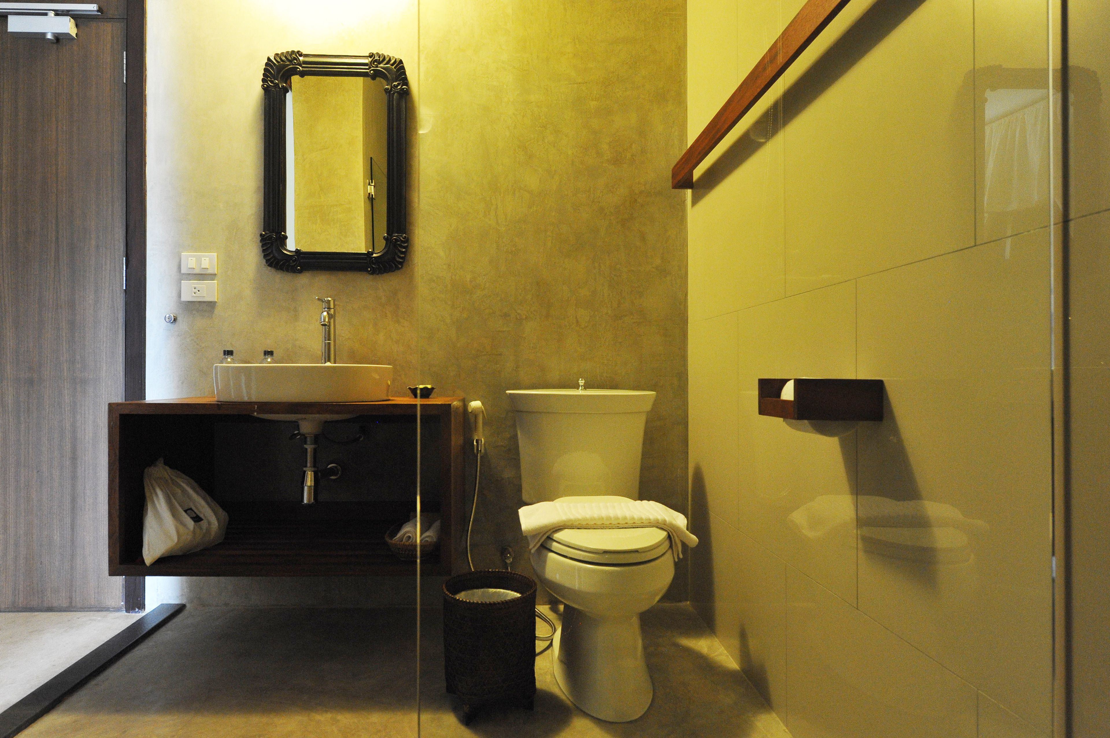 A bathroom with a sink, mirror, toilet, and a trash bin.