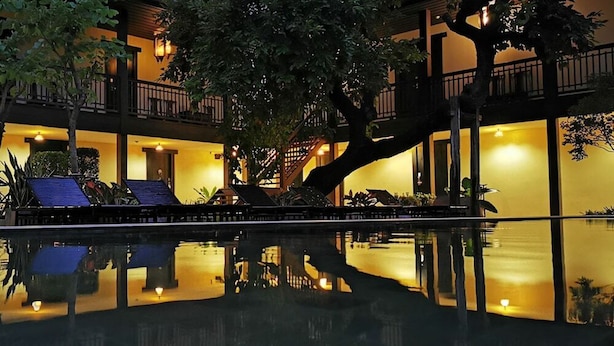 A hotel with a reflective pool, outdoor seating, and warm lighting.