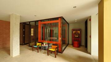 A modern room with a glass partition, a small table with chairs, and a red vending machine.