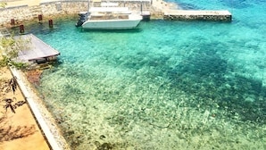 Een boot aangemeerd aan een steiger met helder turquoise water en een zandstrand.