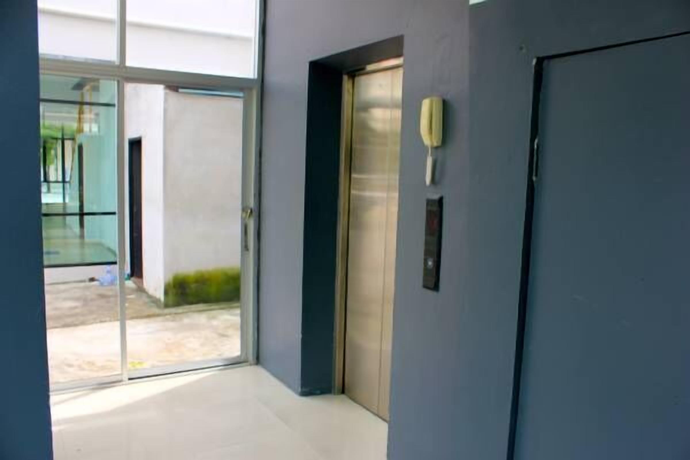 A modern elevator with a glass door, a wall-mounted phone, and a small plaque.