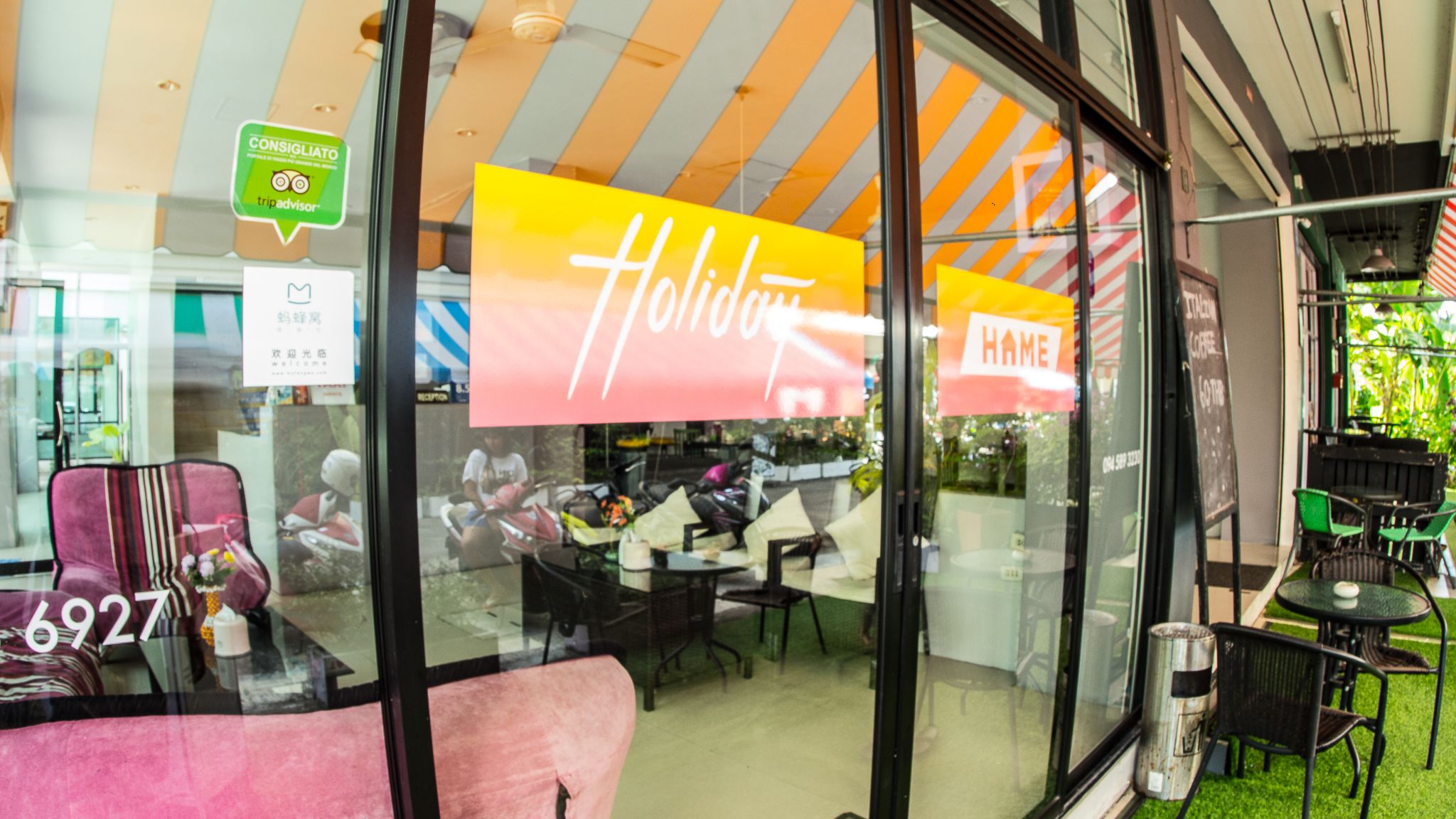 A restaurant with a 'Holiday' sign, outdoor seating, and a 'HAME' sign.