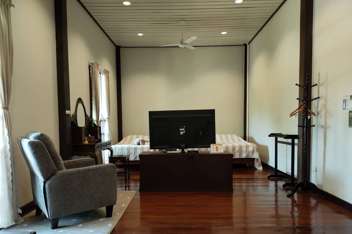 A hotel room with a bed, a TV, a chair, a desk, and a coat rack.
