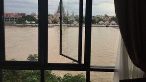 Blick durch ein Fenster auf einen Fluss, mit Gebäuden und einem Tempel im Hintergrund.