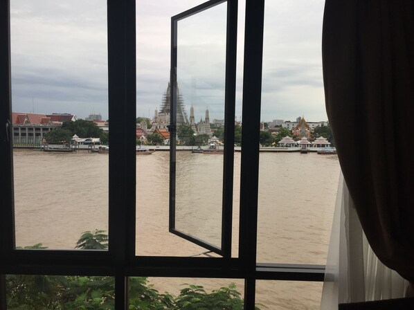 Vista a través de una ventana que muestra un río con edificios y un templo al fondo.