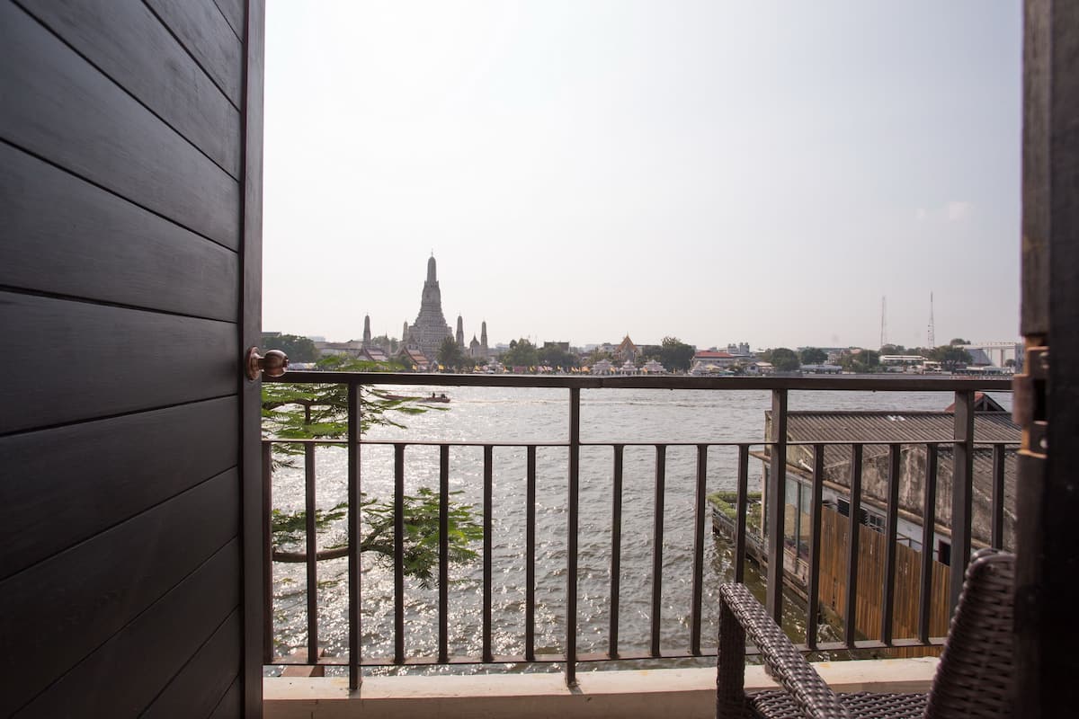 A balcony with a view of a river and a distant temple.