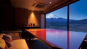 A room with a large table, a sofa, and a view of a snow-capped mountain.