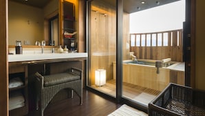A modern bathroom with a large mirror, a wooden vanity, a bathtub, and a wicker chair.
