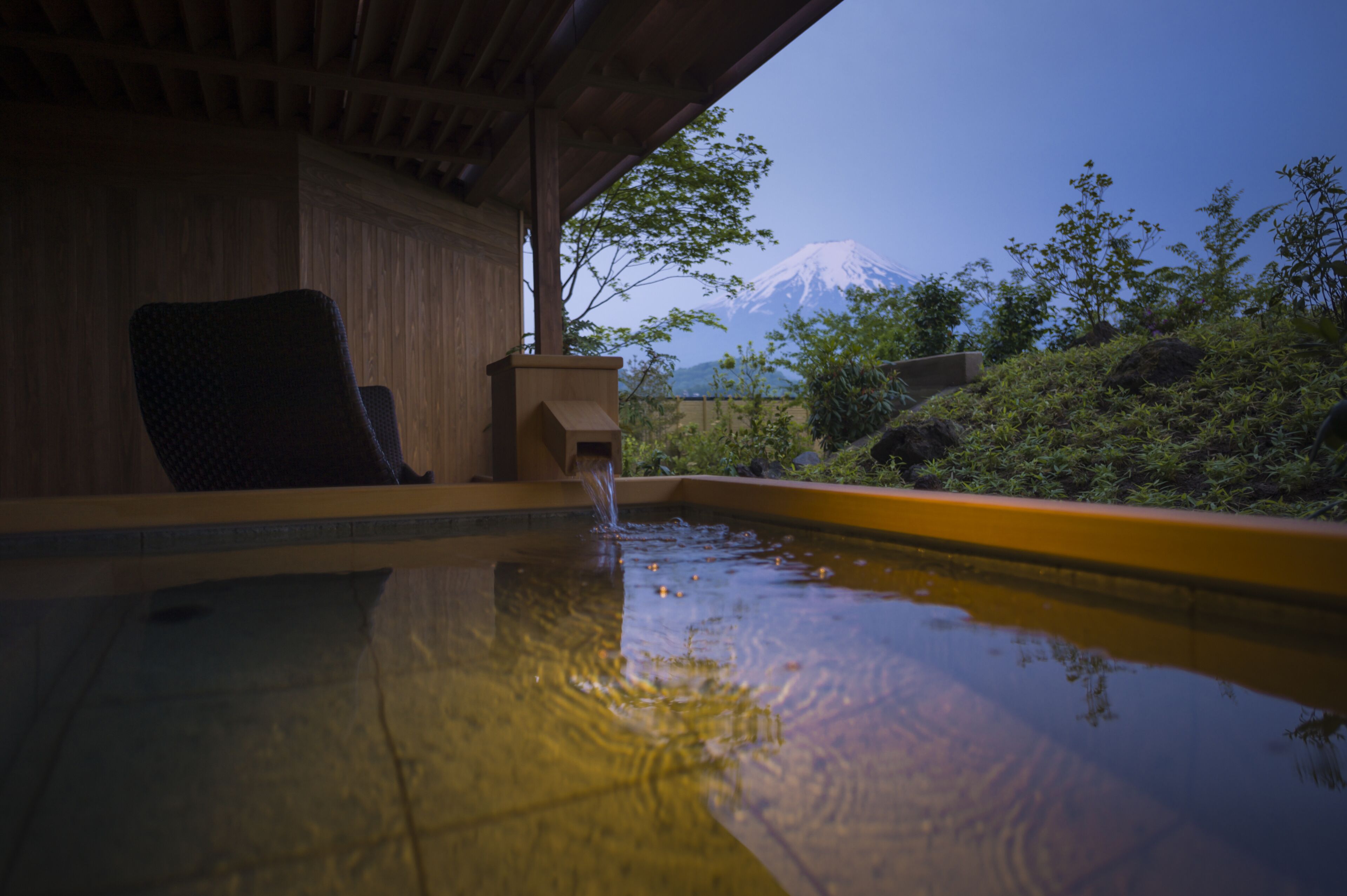 A hot spring area with a wooden chair and a view of a snow-capped mountain.