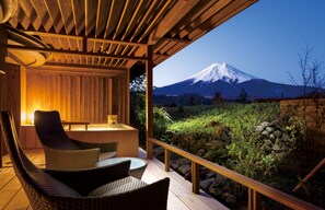 Une terrasse en bois avec des chaises et une table en osier, offrant une vue sur une montagne enneigée.